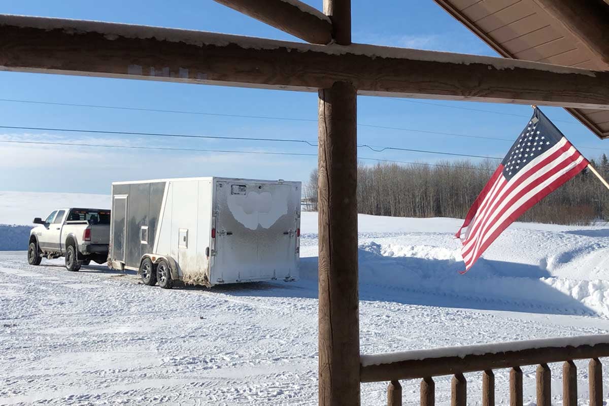 EZ Hauler 3-Place Inline Snowmobile trailer parked on a snowy driveway viewed