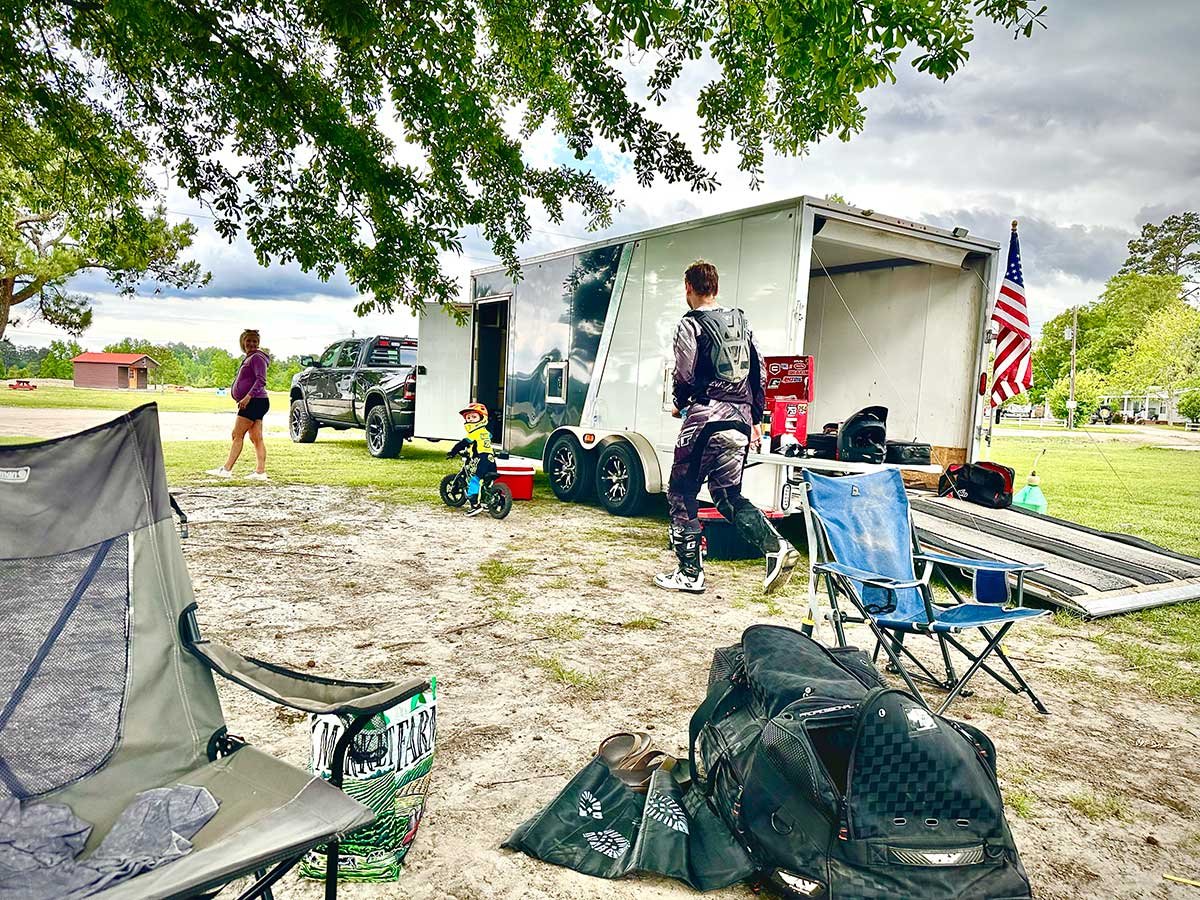 Paul's 3-place inline snow trailer parked outside with dirtbikes and chairs set up on a summer day