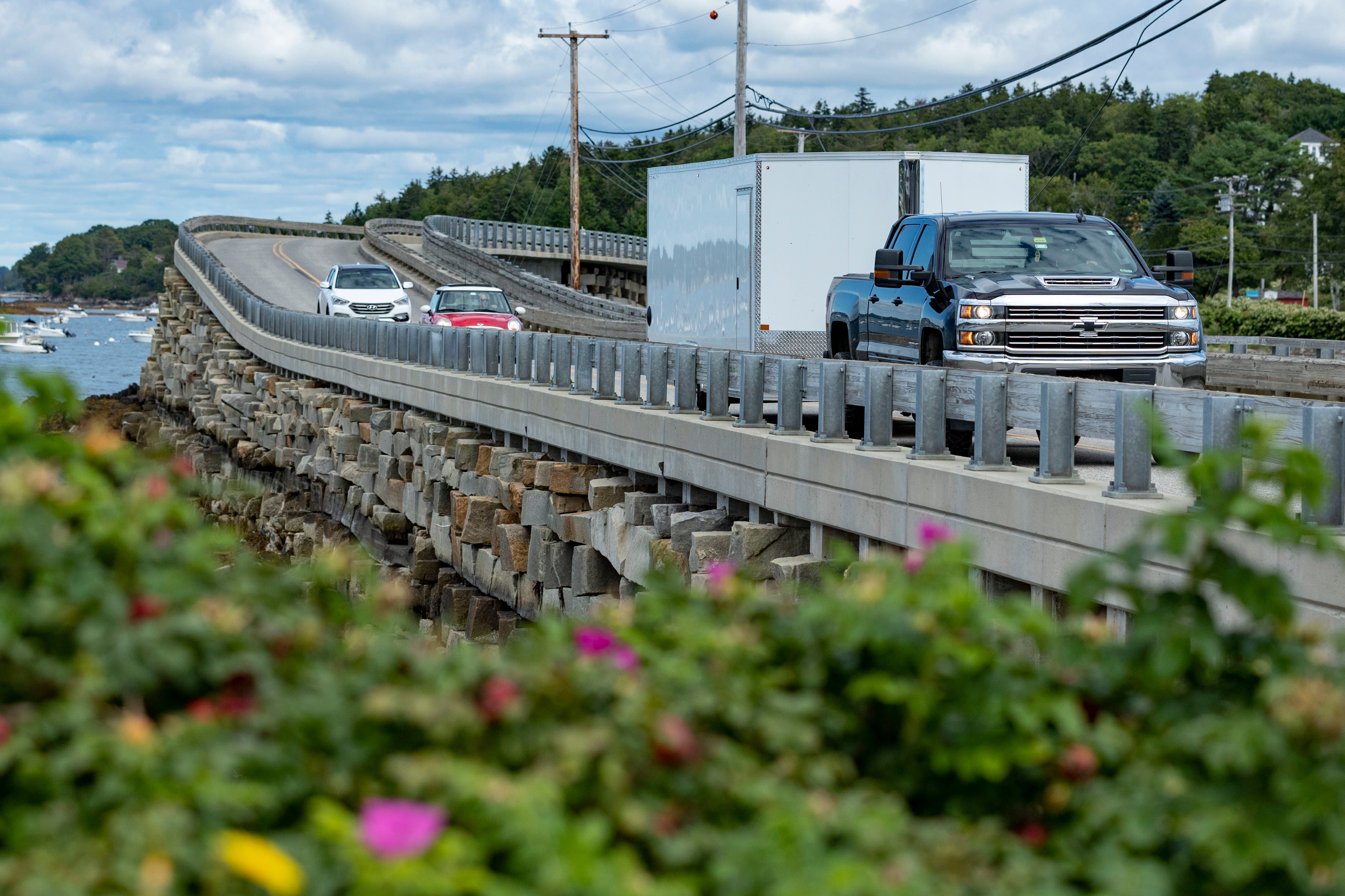 A pickup truck tows an enclosed ALCOM aluminum trailer on Orrs Island Maine on a summer day