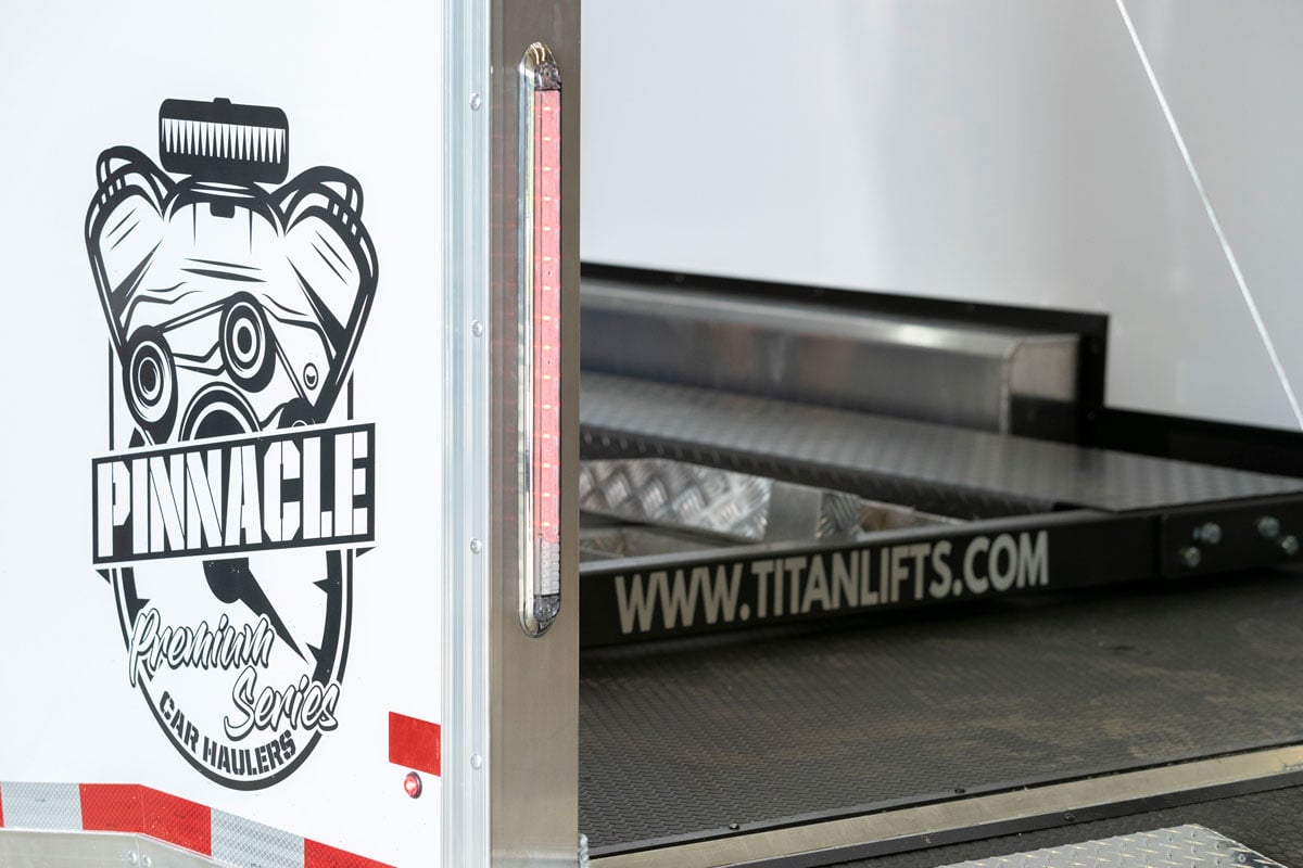 White Pinnacle Stacker Series aluminum racecar trailer with ramp door open showing 6k Titan lift