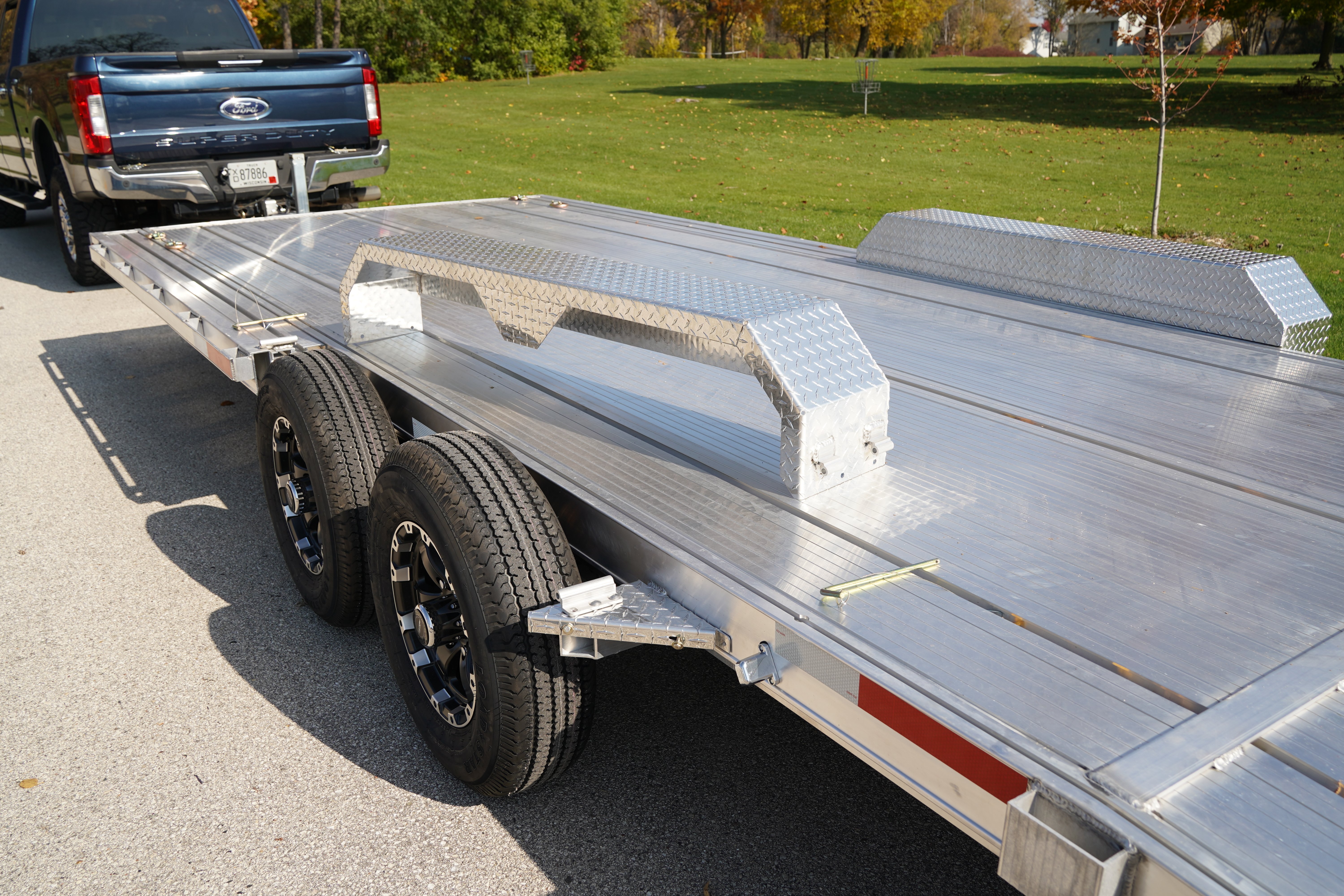 A Triton Trailers open HD car hauler/utility trailer hitched on to a blue pickup