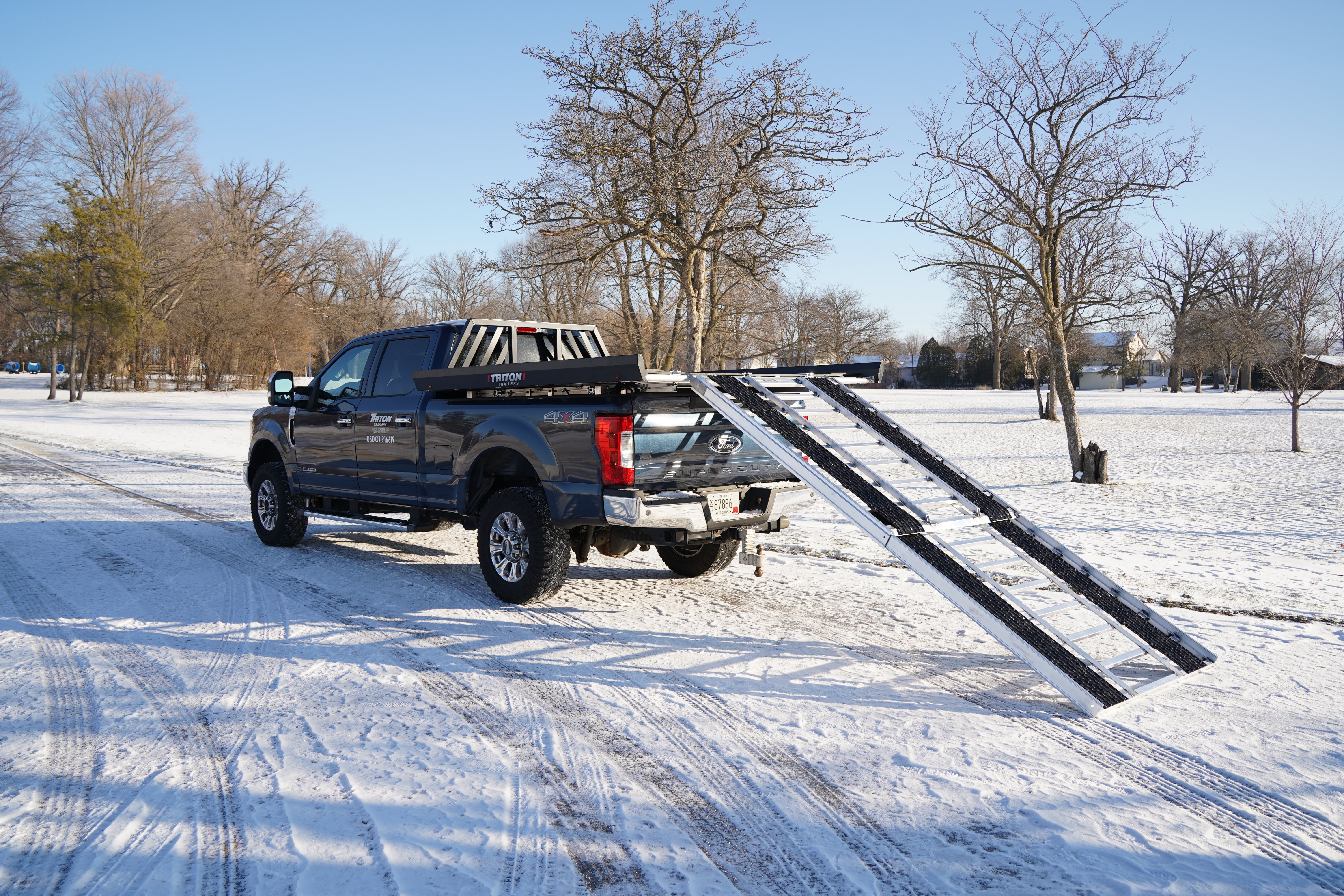 An aluminum Triton sport deck mounted in a pickup truck with the ramps extended