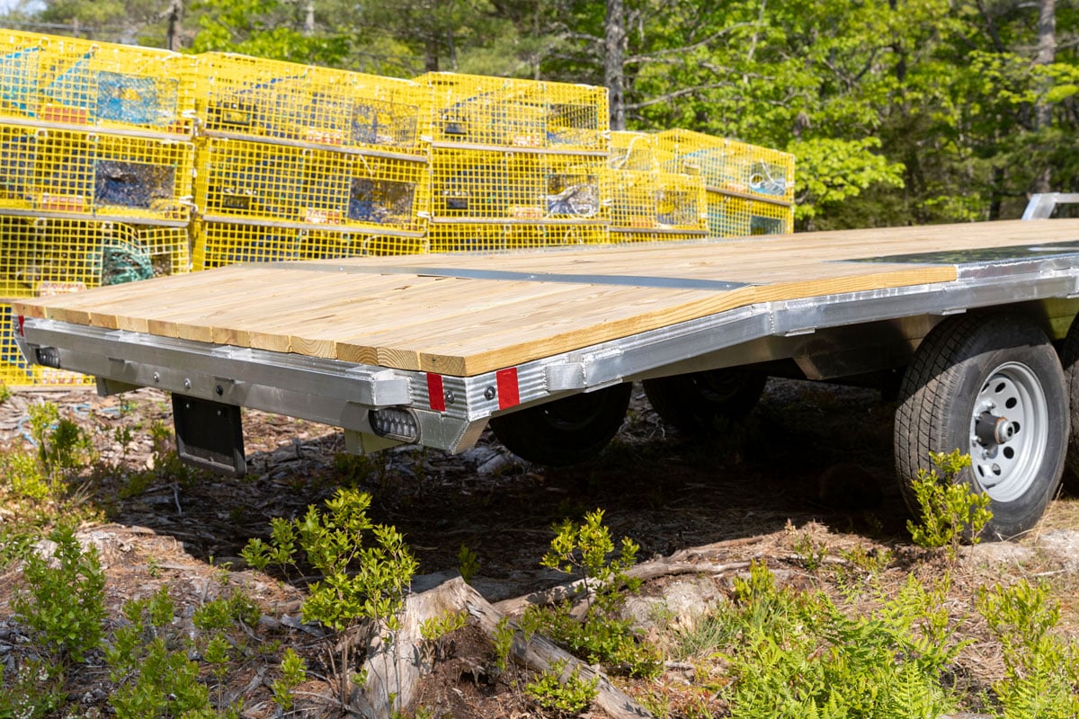 Deckover wood deck utility trailer shown parked by a stack of lobster traps