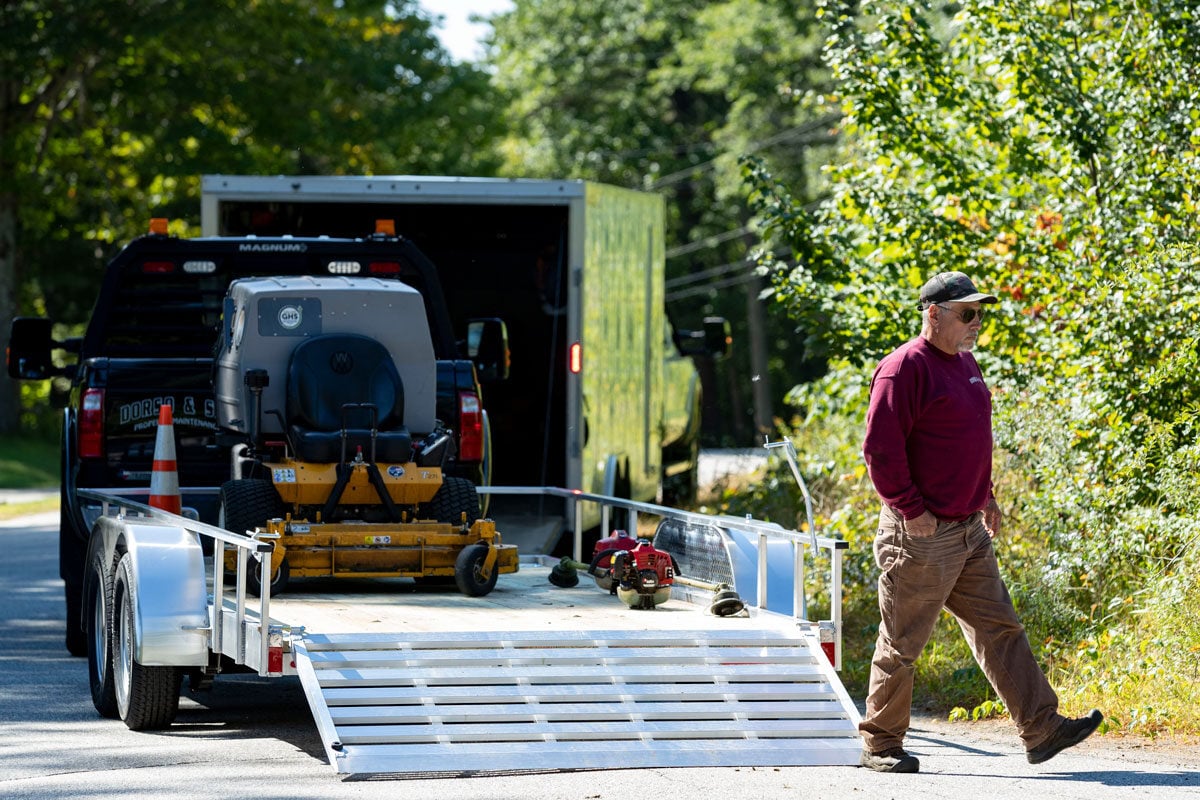 Open utility wood deck tandem axle aluminum utility trailer on the job with a landscape crew