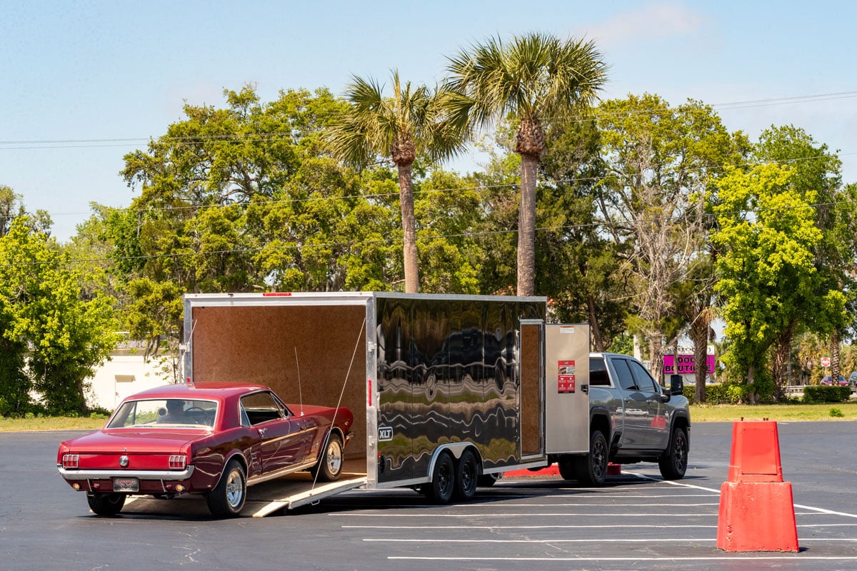 Red classic Mustang loading into the parked XLT Pro Series car hauler trailer