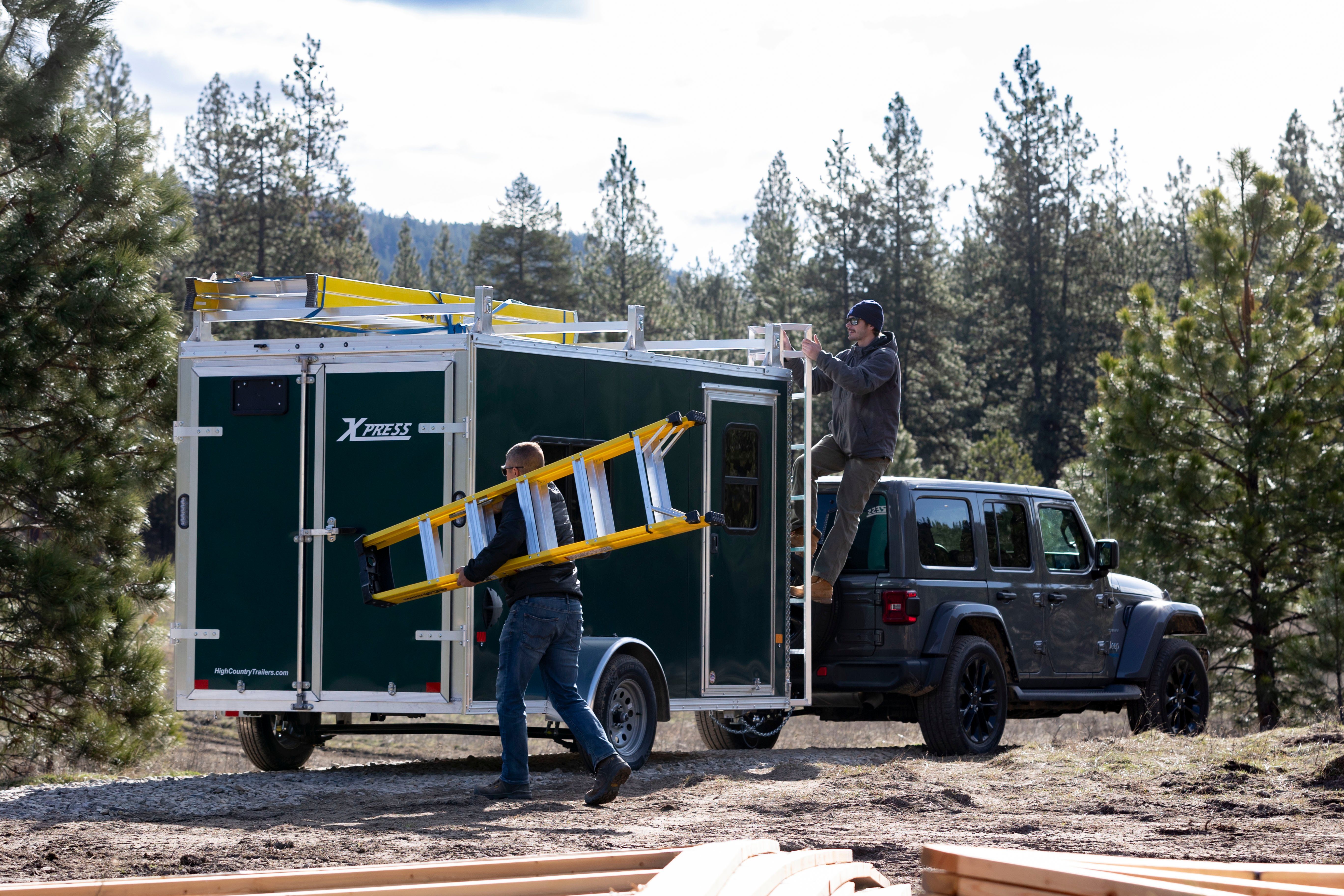 Two people using the ladder racks on an enclosed aluminum contractor trailer