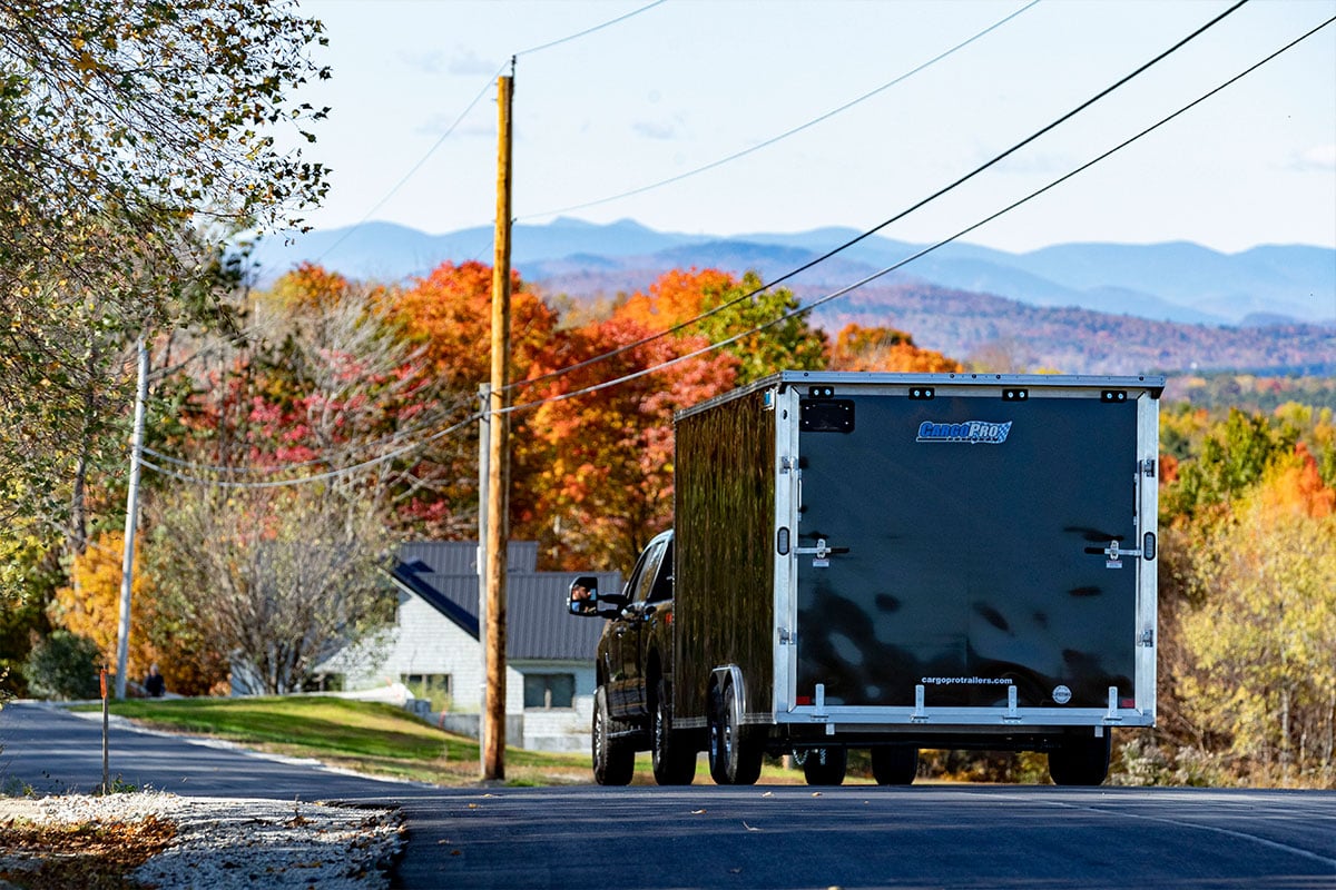 A well maintained enclosed aluminum cargo trailer on the road during fall