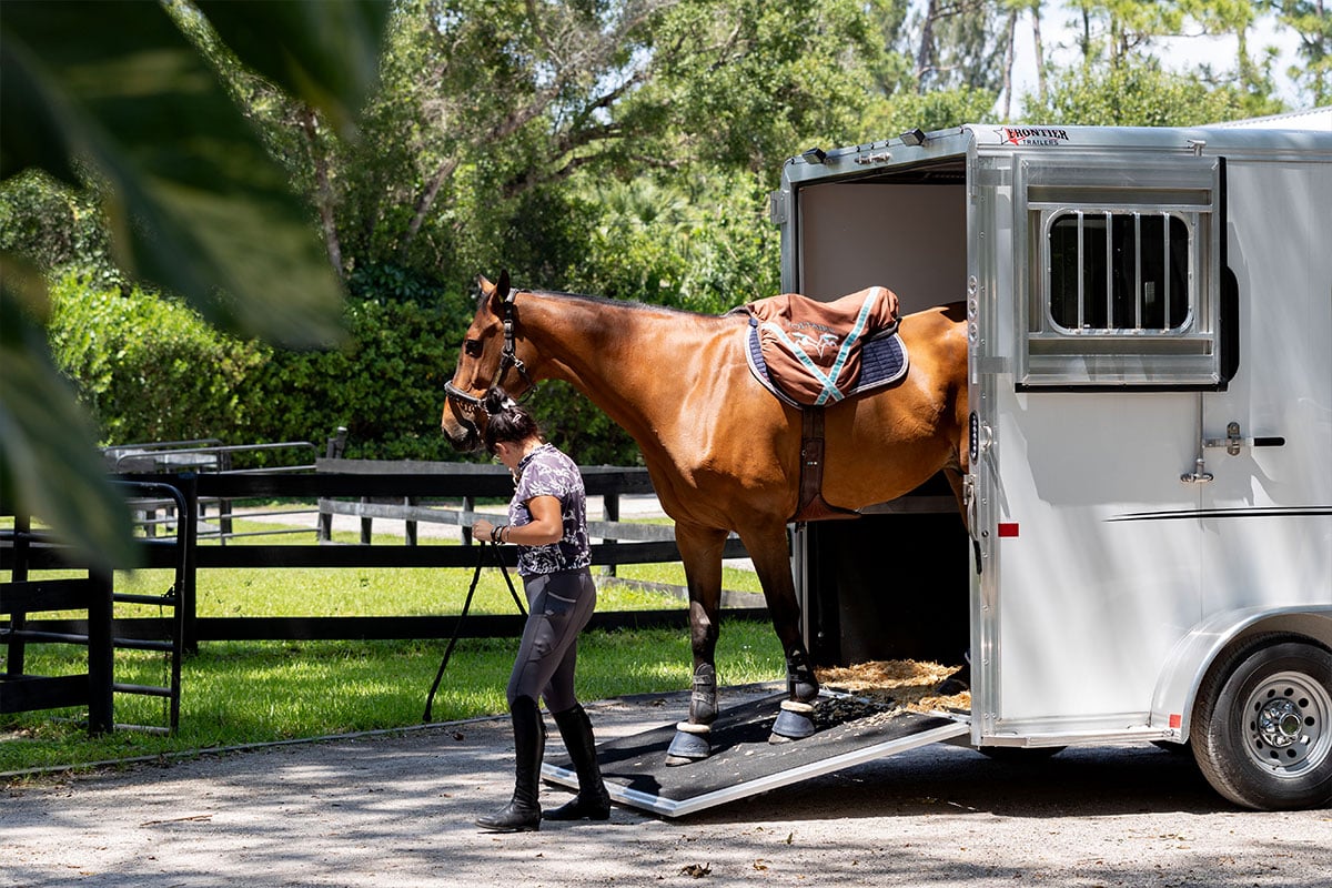 A woman leads a horse out of a Frontier aluminum trailer