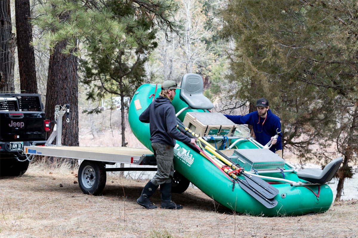 Two guys unloading an inflatable fishing raft from a Mission aluminum raft trailer in Montana