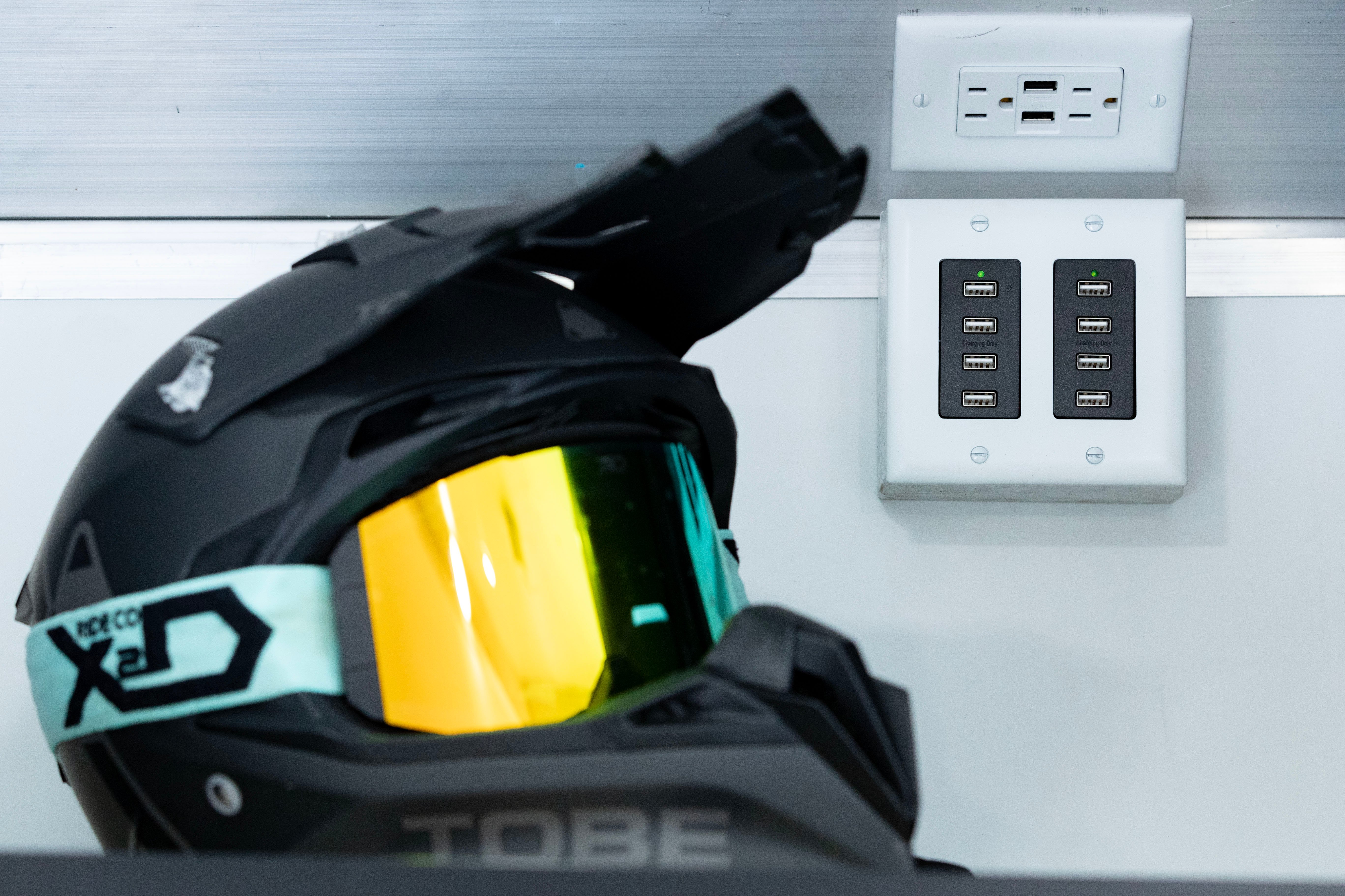 USB outlets inside an enclosed ALCOM aluminum trailer with a helmet and goggles placed beside outlet