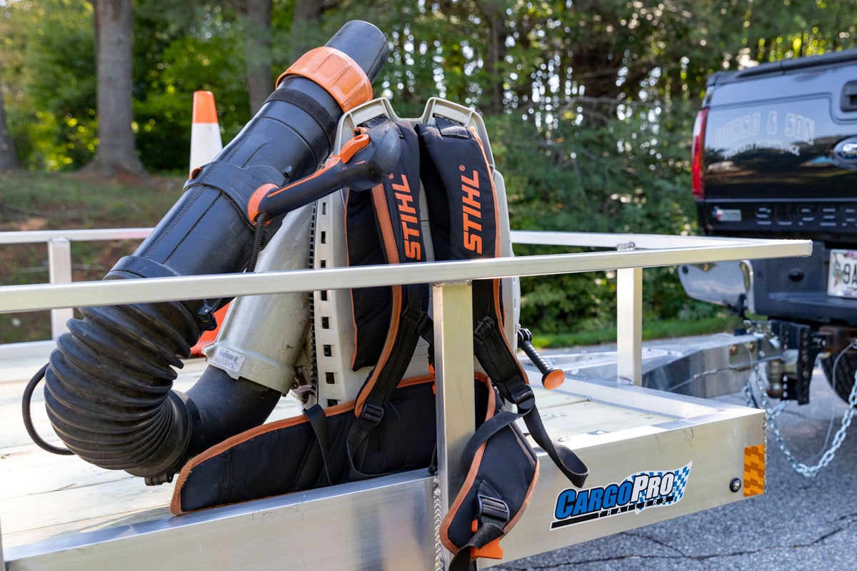 Leaf blower sitting on a CargoPro open aluminum utility trailer at a landscaping and lawn care jobsite