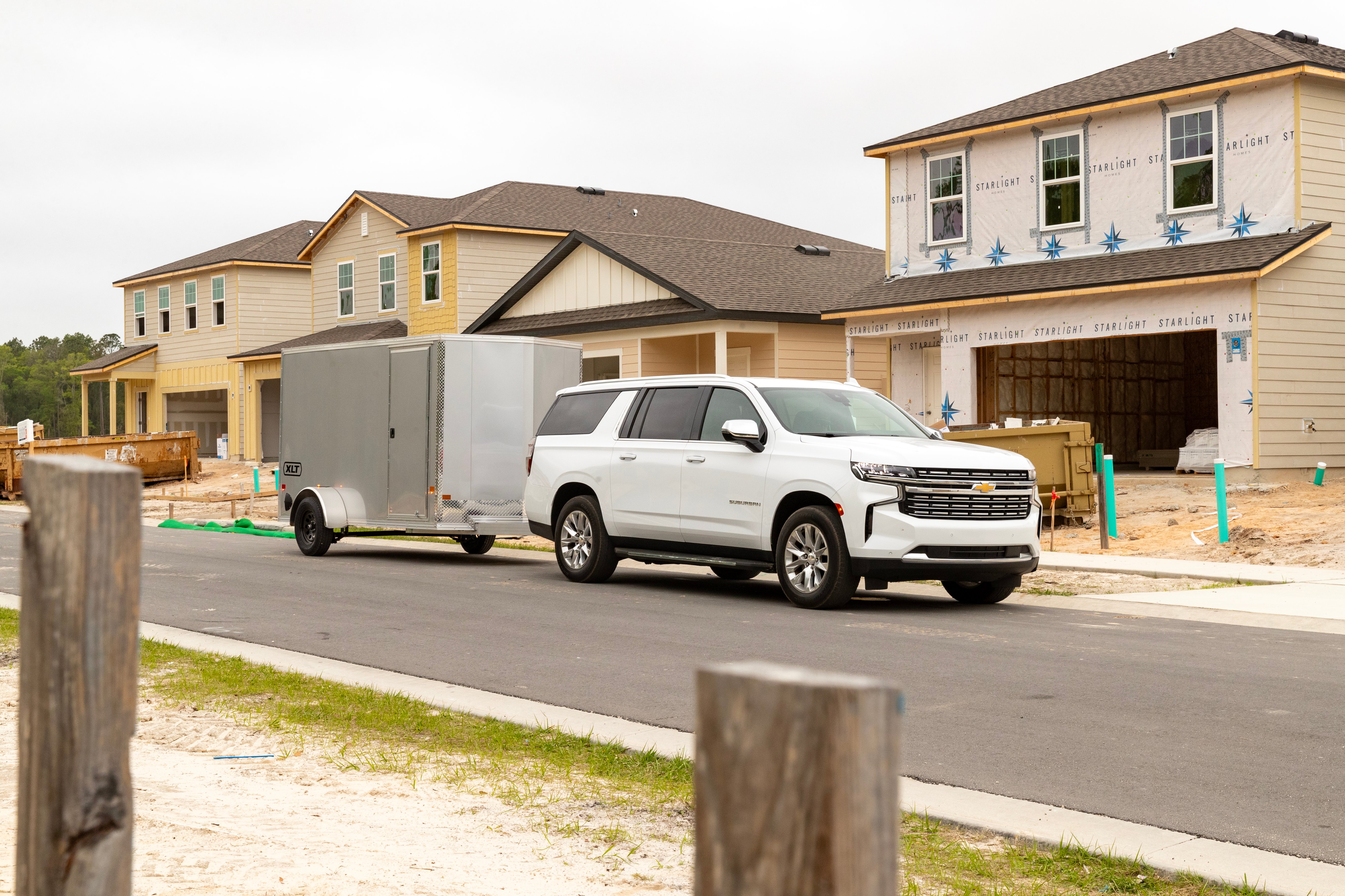 A silver 6' wide XLT Pro Series trailer towed by a white SUV through a construction area