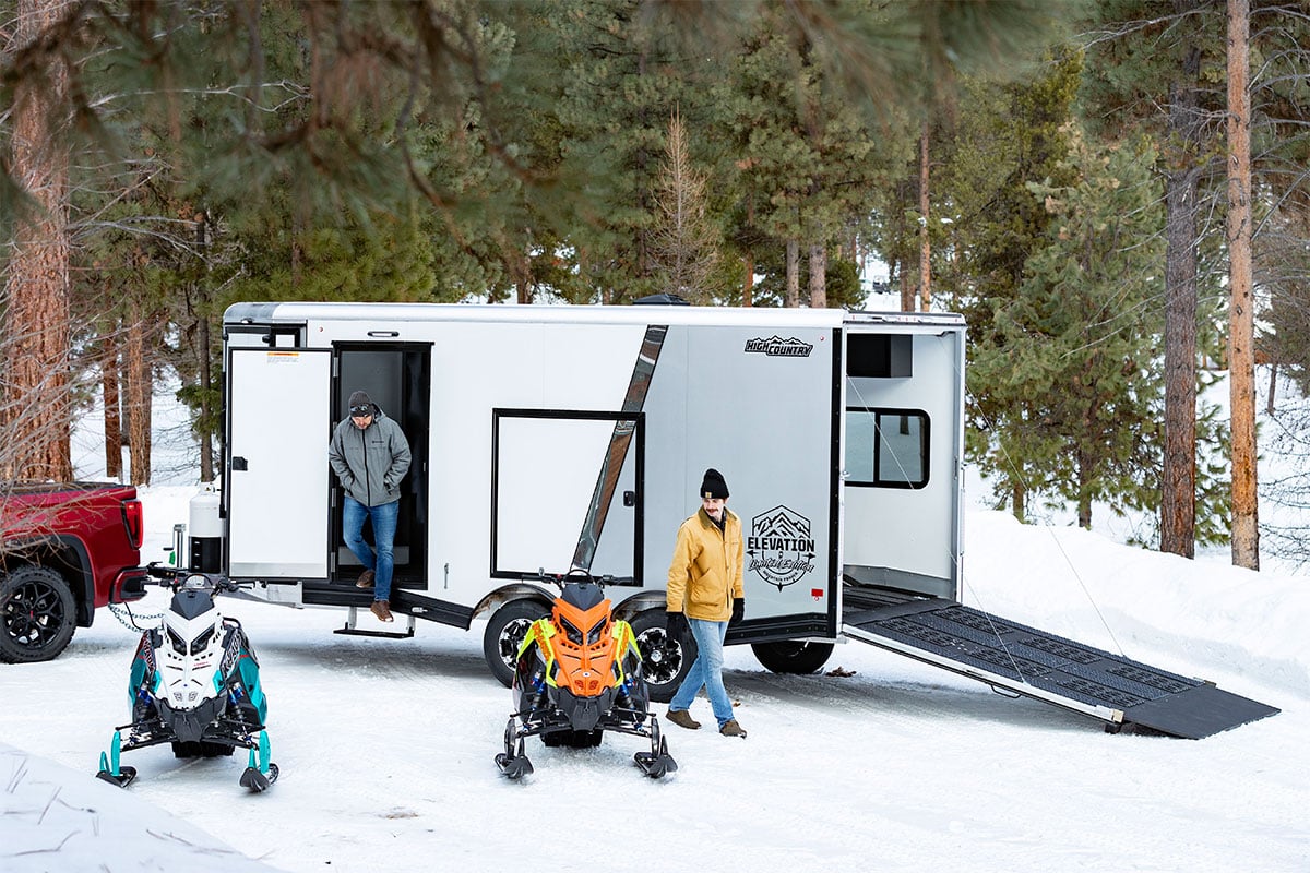 All-Sport Elevation trailer parked with snowmobiles at a cabin