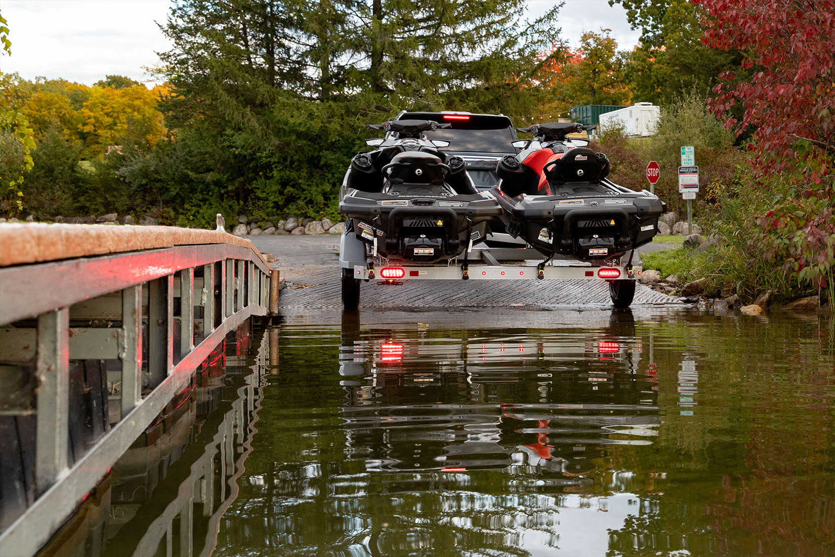 Triton aluminum PWC trailer with two jetskis backing into the water