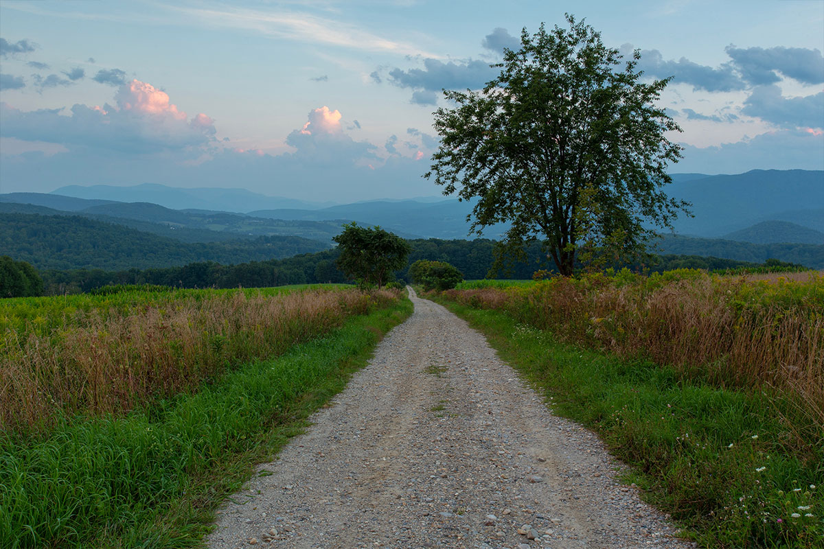 Dirt road at sunset in Vermont, with mountains in the background