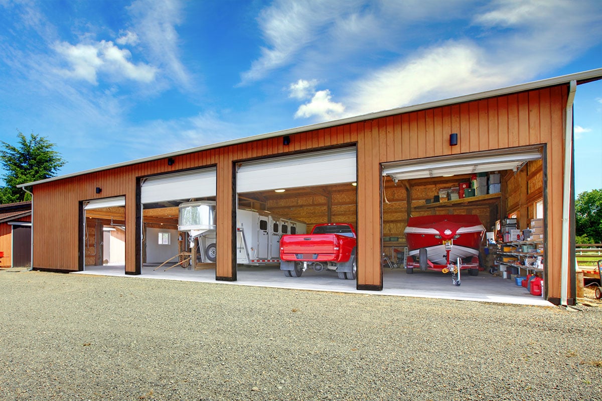 A four-bay garage with multiple vehicles and trailers parked inside.