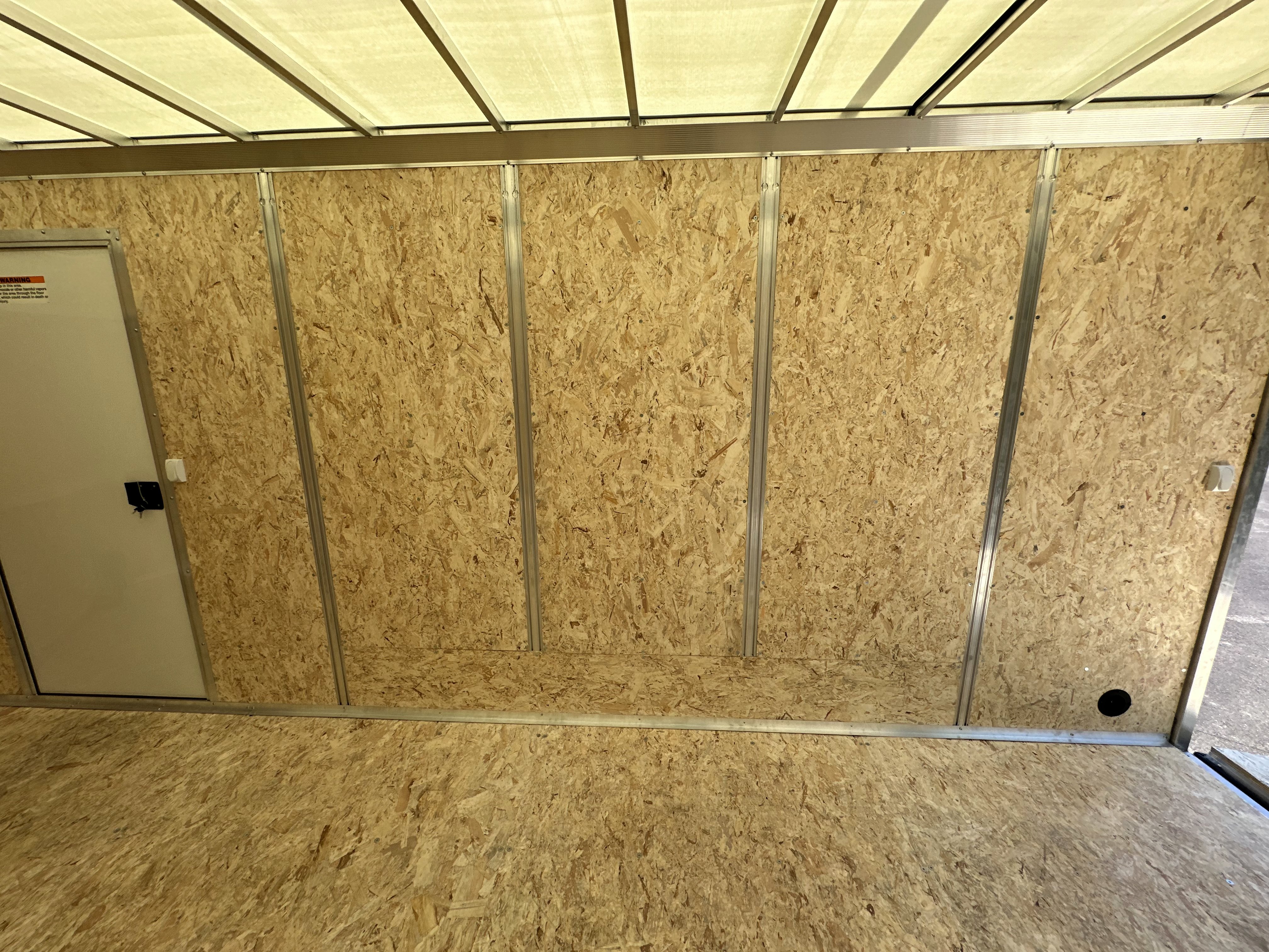 Integrated wall studs and access door on the curb side interior of an aluminum trailer