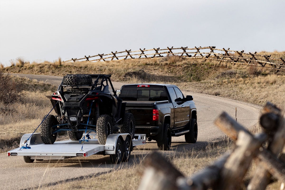 Open aluminum trailer by ALCOM with ATV secured using tie down straps and D-rings 