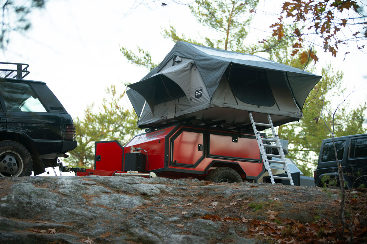 An AO Trailers Spur Offroad camper trailer set up for camping on a rocky mountaintop