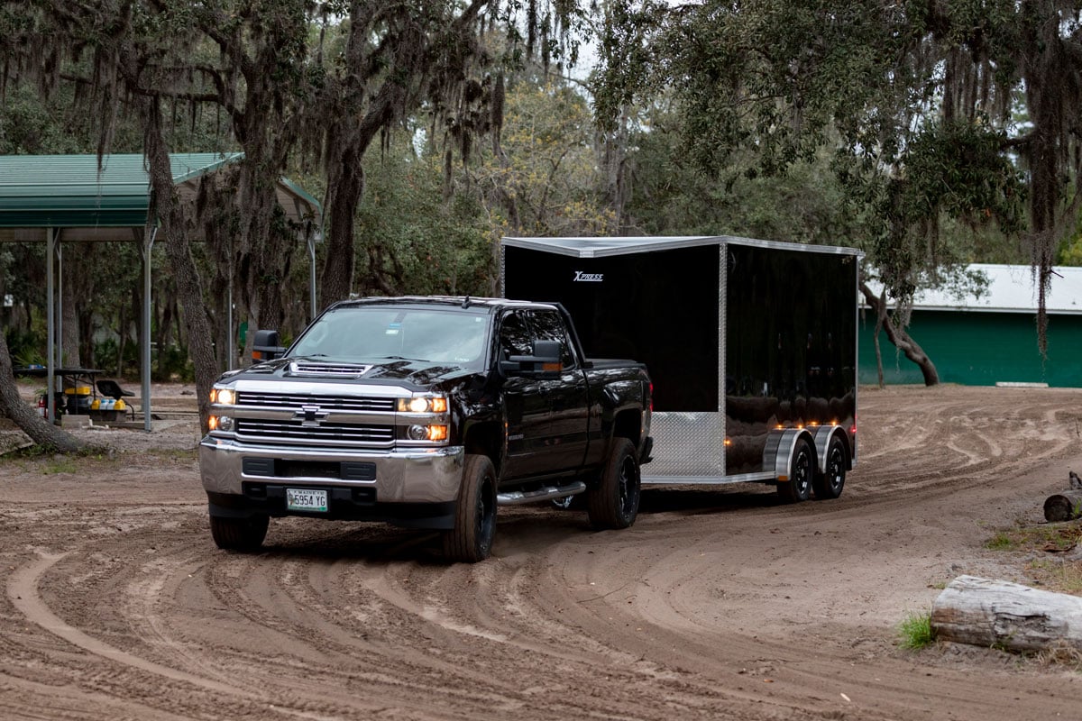 Enclosed UTV trailer towed by a truck on a dirt road in Florida