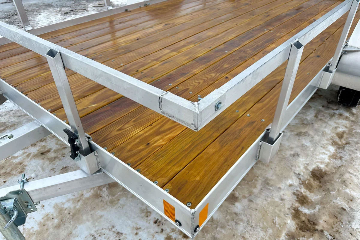 Fixed 2 by 2 aluminum rail kit installed in stake pockets on an open ALCOM trailer