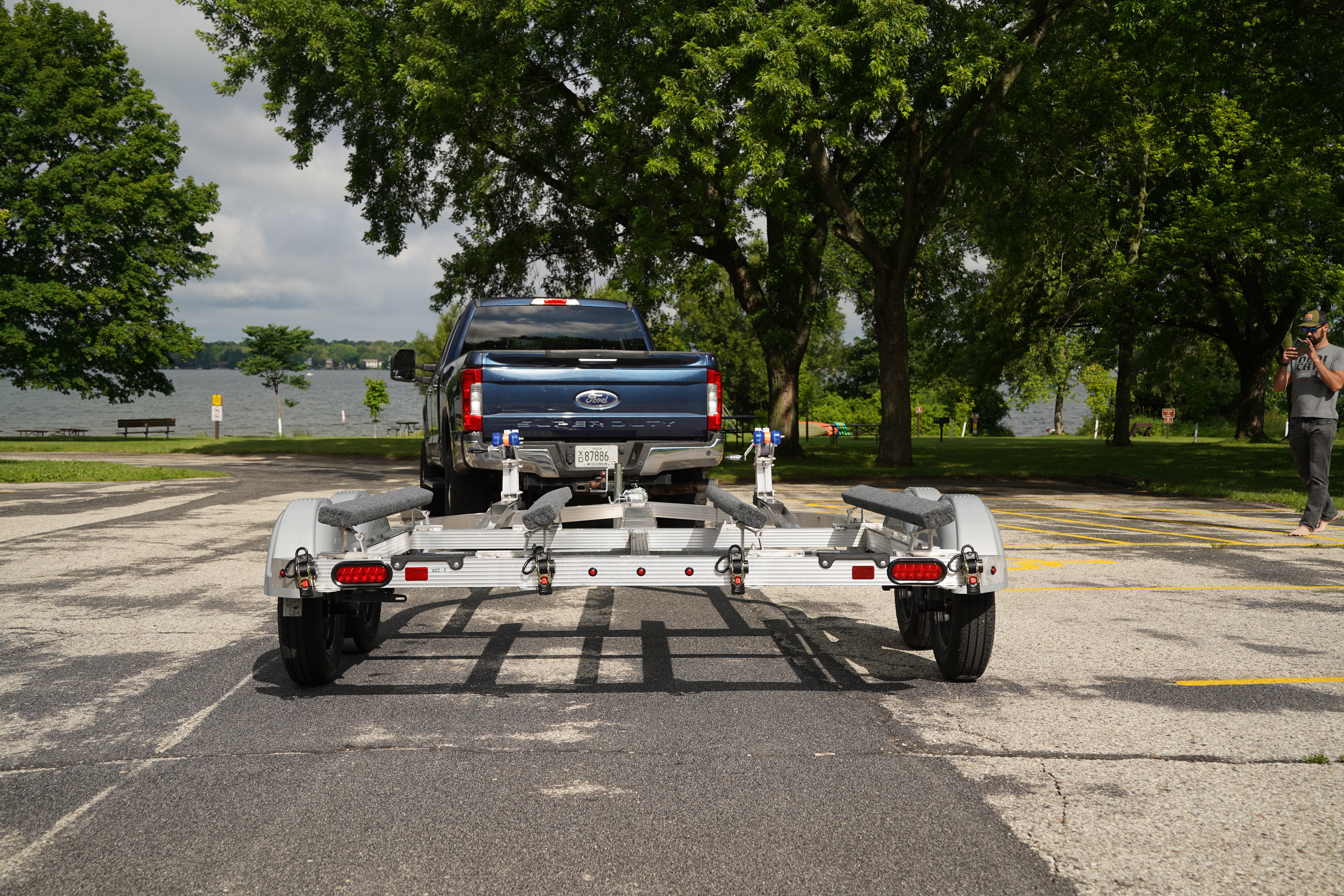 A blue pickup towing an unloaded Triton Trailers aluminum PWC trailer to the boat ramp 