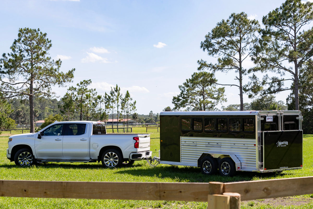 A Stock LowPro DDFW trailer hitched to a silver truck parked in a grassy field