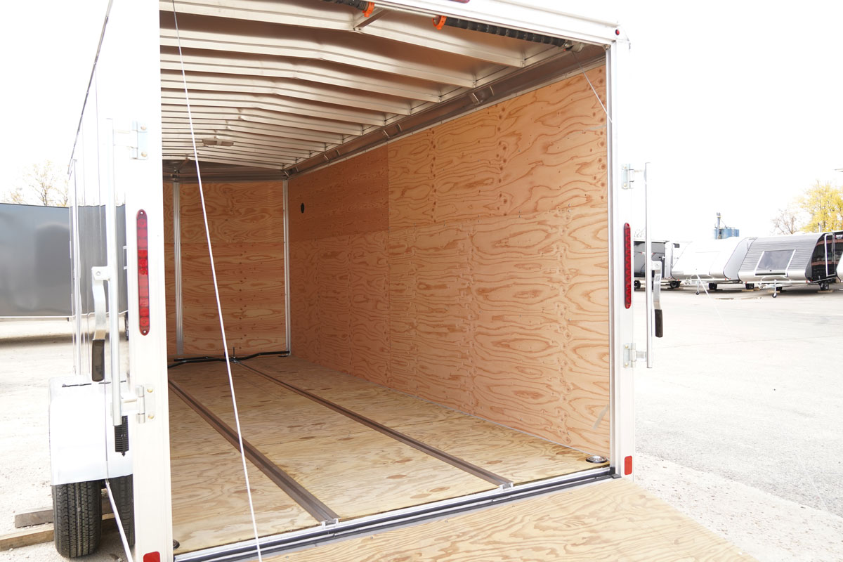 ALCOM aluminum cargo trailer with rear ramp door open showing water resistant walls, decking, and versatile slide tracks