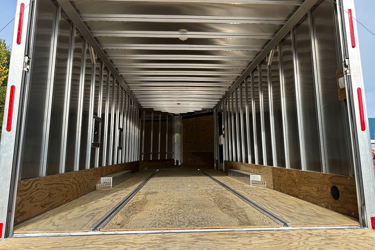 Plywood decking and kick plate inside cargo trailer with installed slide track