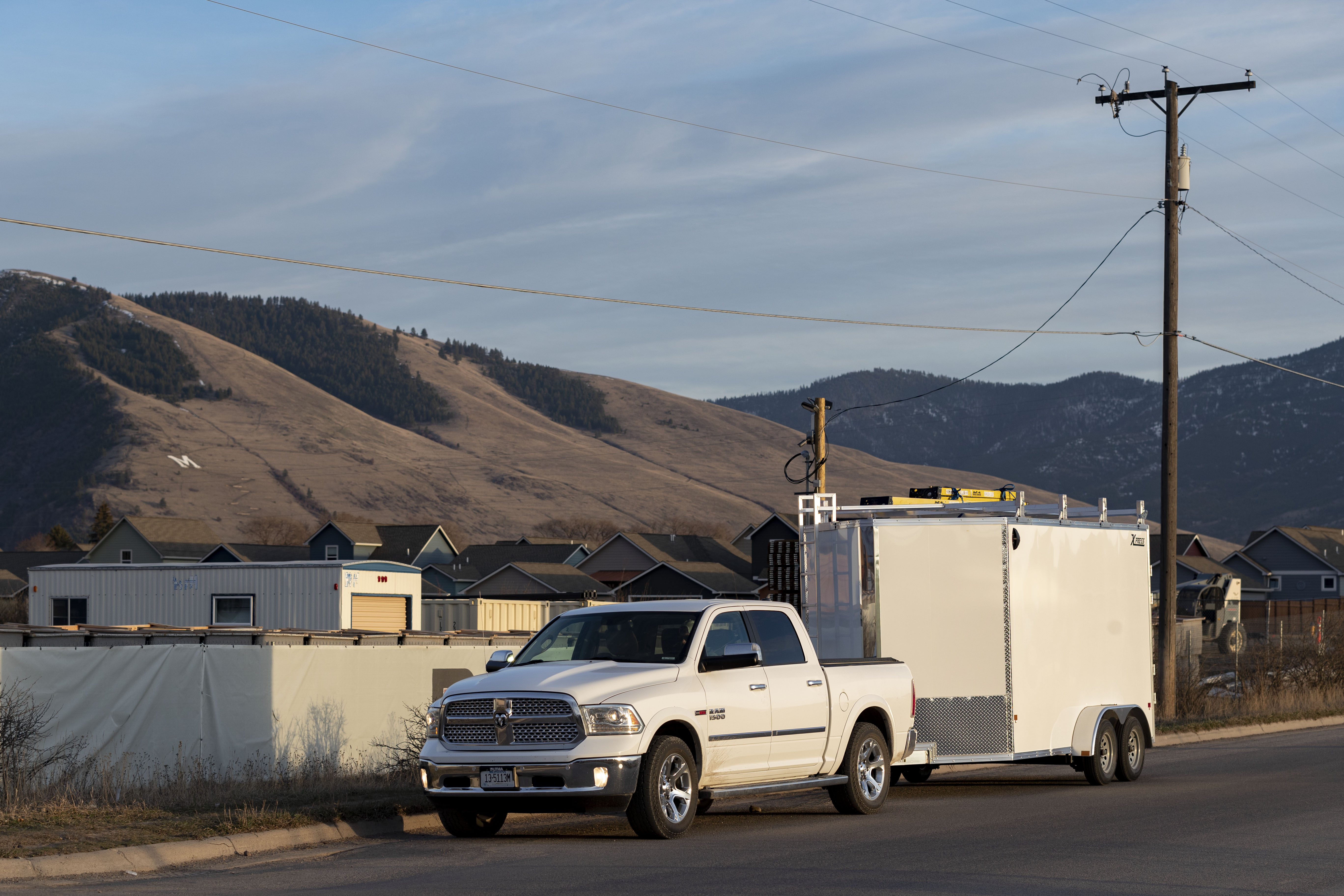 A white pickup and white Ultimate Contractor Package trailer parked at a jobsite with mountains in the background